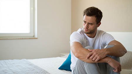 Мужчина обнимает колени